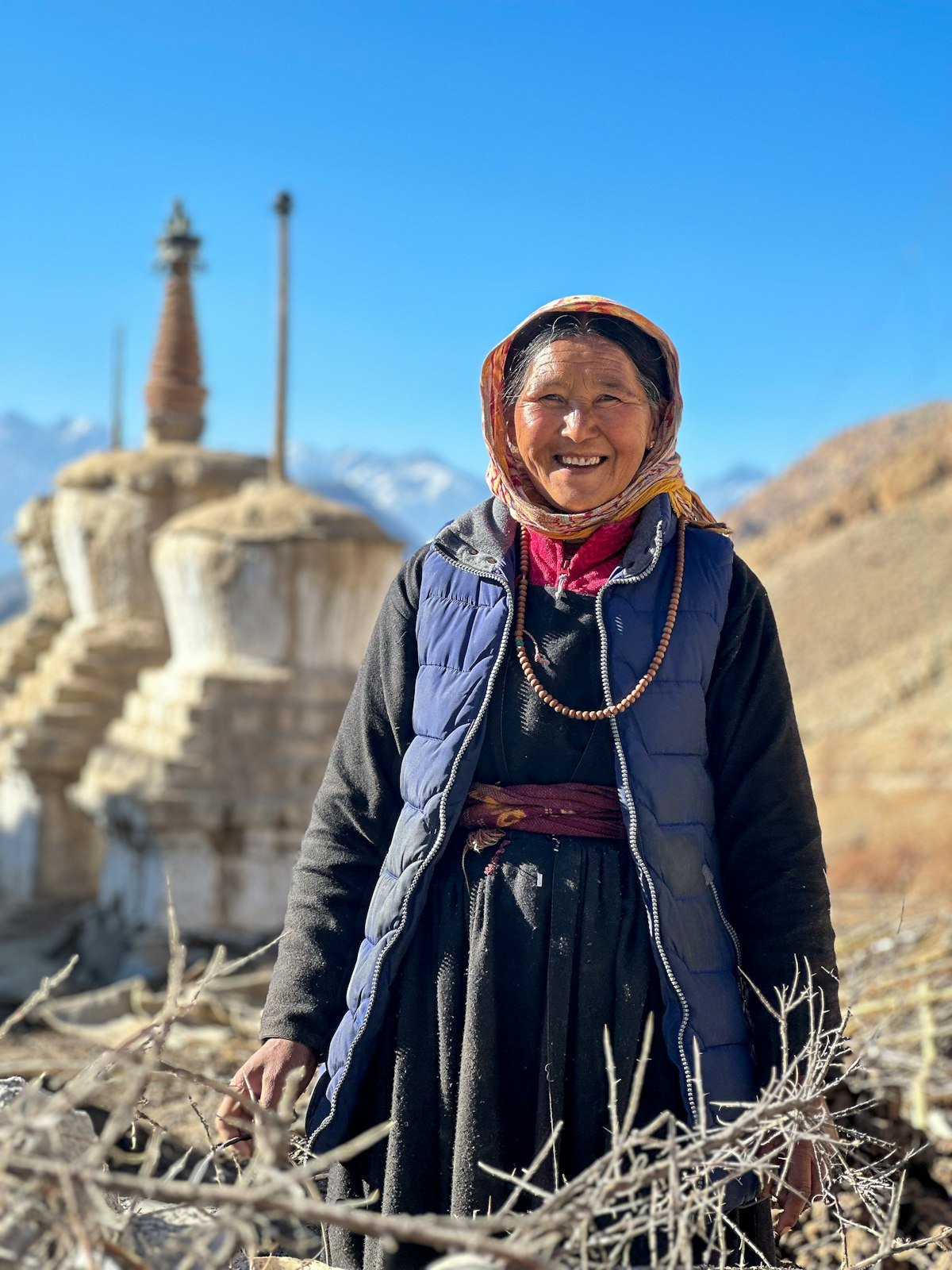 A woman standing in a field with mountains behind her